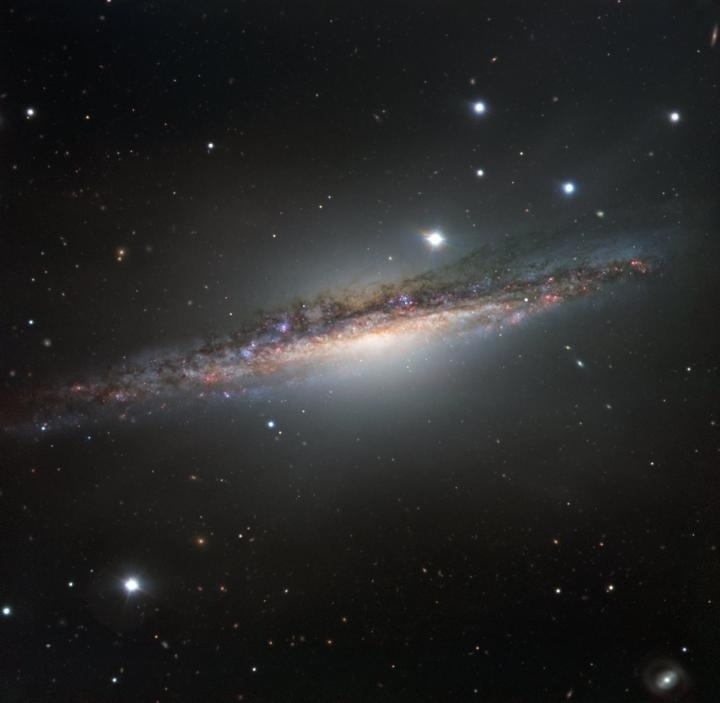 1º.mar.2017 - NA BORDA DA GALÁXIA - Observando as galáxias que existem no universo é possível ver muitos focos do núcleo galáctico, mas é difícil ter uma noção tridimensional. A melhor forma de ter uma visão geral de como as estrelas estão se formando seria olhar ?pelas bordas? e é isso que os cientistas estão observando na galáxia NGC 1055. Ela parece não possuir os braços giratórios característicos de uma espiral. No entanto, exibe estranhas torções em sua estrutura, que foram provavelmente causadas por uma interação com uma grande galáxia vizinha. A imagem foi registrada pelos telescópios formam o VLT (Very Large Telescope), maior conjunto de telescópios ópticos do mundo. Com essa perspectiva, os astrônomos devem  conseguir estudar a forma geral de um disco galáctico e suas propriedades