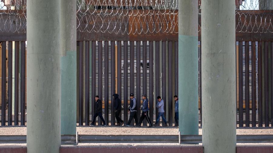 17 mar. 2021 - Migrantes indocumentados caminham ao longo de muro na fronteira EUA-México depois de correrem no rio Grande, na Ciudad Juarez, México - John Moore/Getty Images