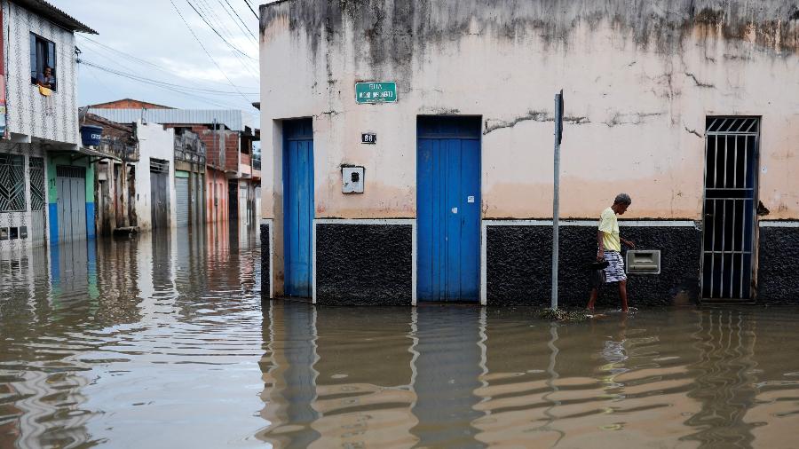 27.dez.2021 - Pessoa caminha na água ao longo de uma rua durante enchentes causadas por fortes chuvas em Itajuípe, Bahia - Amanda Perobelli/Reuters