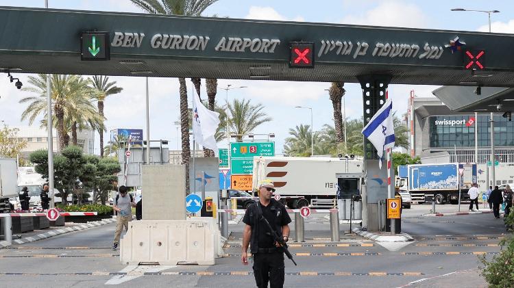 Agente de segurança se posiciona na entrada do aeroporto Ben Gurion após um míssil lançado do Iêmen cair próximo ao terminal