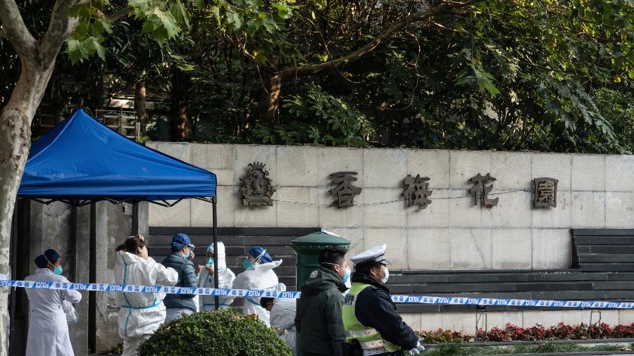 26.nov.2021 - Policiais e membros da equipe médica são vistos fora de uma área residencial que está sob restrições após um recente surto de coronavírus em Xangai  - AFP