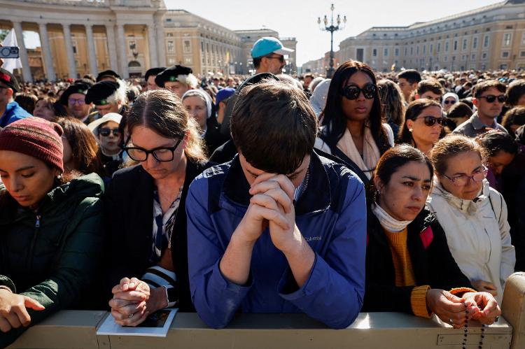 Pessoas rezam enquanto aguardam o início da missa fúnebre do Papa Francisco, na Praça de São Pedro, no Vaticano, em 26 de abril de 2025 Pessoas rezam enquanto aguardam o início da missa fúnebre do Papa Francisco, na Praça de São Pedro, no Vaticano, em 26 de abril de 2025