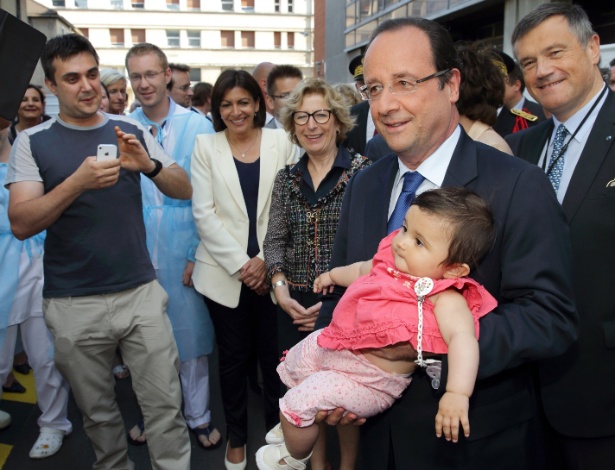 Presidente francês François Hollande segura um bebê ao chegar a um hospital de Paris - Philippe Wojazer/AFP