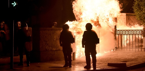 Bomba incendiária explode diante de policiais durante manifestação em Atenas contra o pacote de reformas imposto por credores do país como condição para um novo socorro aos bancos gregos, em 22 de julho - Aris Messinis/AFP