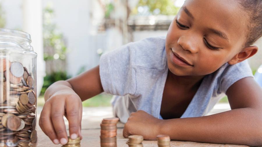 criança contando dinheiro, mesada, finanças pessoais - Getty Images