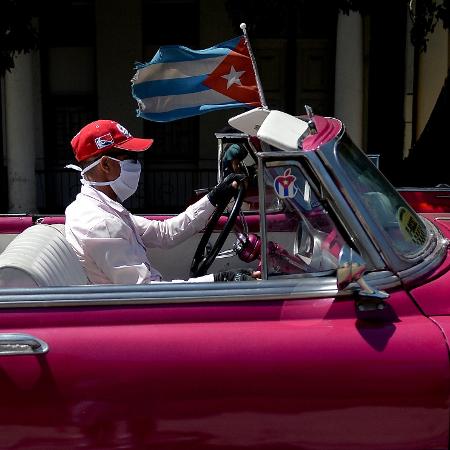 Taxista dirige carro americano antigo pelas ruas de Havana, em Cuba, com máscara no rosto para proteção contra o covid-19 - Yamil Lage/AFP