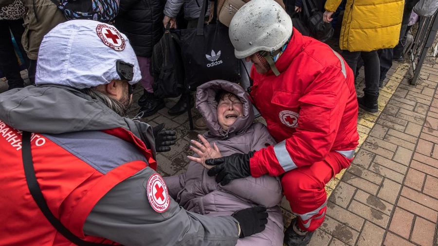 04.mar.22 - Membros da Cruz Vermelha ajudam uma mulher enquanto ela reage depois que um trem de evacuação partiu para a cidade de Kiev, na estação ferroviária de Irpin, Ucrânia - Romain Pilipey/EFE/EPA