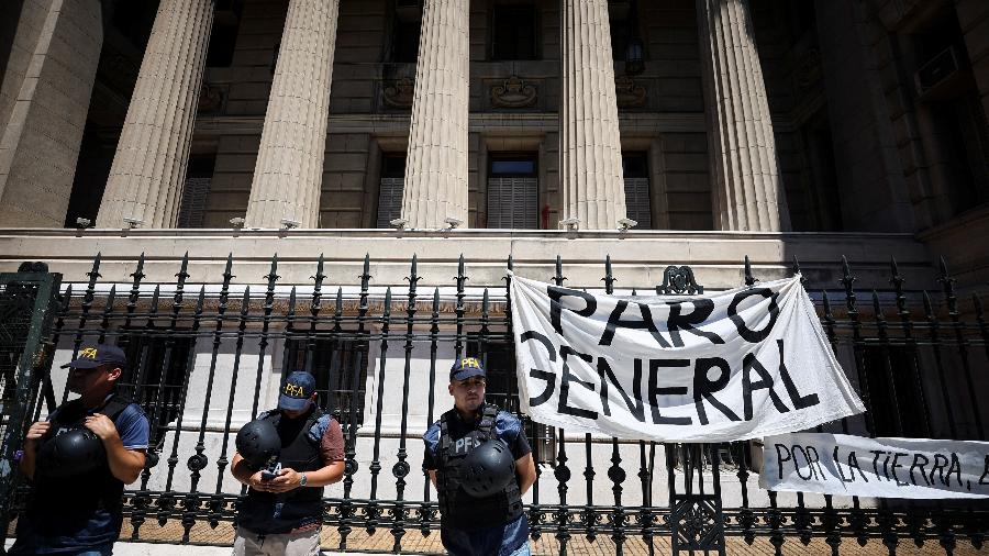 Policiais em frente à bandeira dizendo "greve geral", do lado de fora do Palácio da Justiça em Buenos Aires, na Argentina