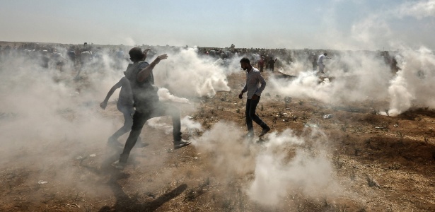 8.jun.2018 - Manifestantes palestinos se protegem de gás lacrimogêneo lançado por soldados israelenses na Faixa de Gaza - Mahmud Hams/AFP