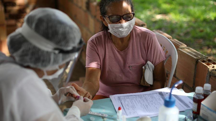 Profissional de saúde realiza teste para a doença covid-19 em uma mulher na Bela Vista do Jaraqui, às margens do rio Negro (AM) - BRUNO KELLY/REUTERS