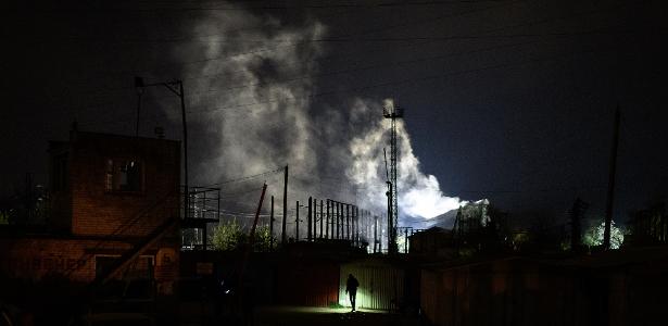 3.mai.2022 - Em meio a fumaça e fogo, policiais vasculham área atingida por ataque em Lviv, no oeste da Ucrânia