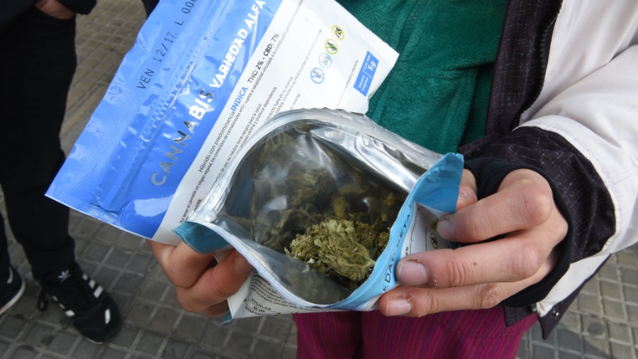 Homem mostra pacote que contém a maconha comprada em farmácia de Montevidéu, no Uruguai - MIGUEL ROJO/AFP