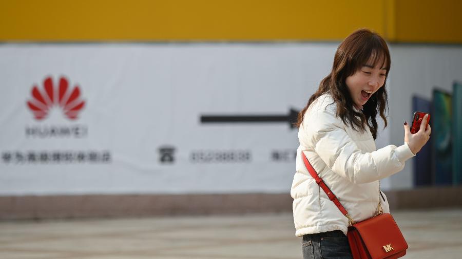Imagem ilustrativa: Mulher sorri para a tela de um smartphone em Pequim, na China - Wang Zhao/AFP
