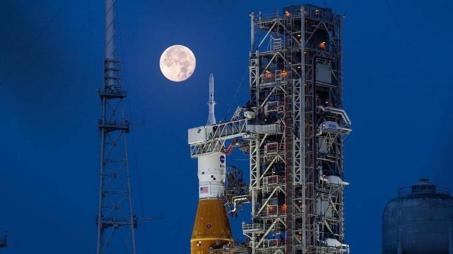 Foguete SLS da missão Artemis com Lua cheia ao fundo