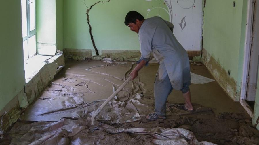 Homem tenta limpar casa após chuvas torrenciais na província de Ghazni, no Afeganistão