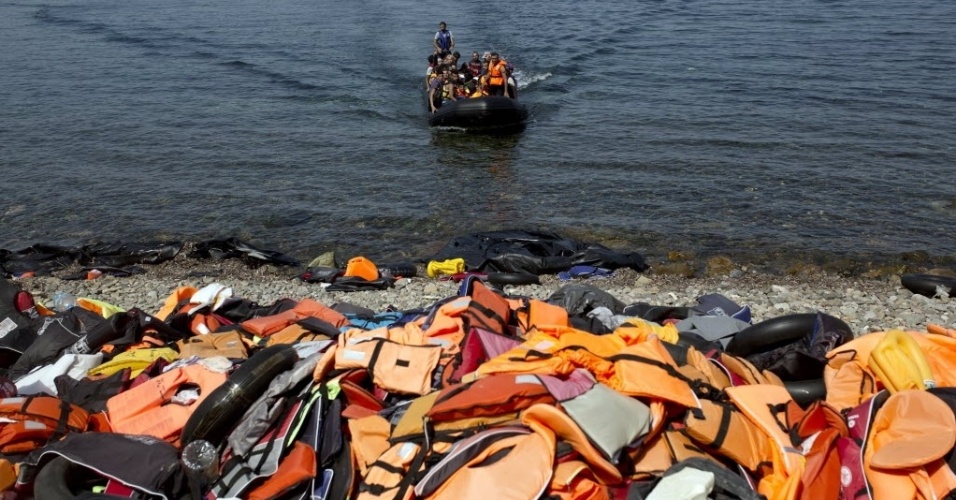 10.set.2015 - Refugiados chegam às margens da ilha grega de Lesbos, lotada de coletes salva-vidas, depois de cruzar o mar Egeu da Turquia em um bote