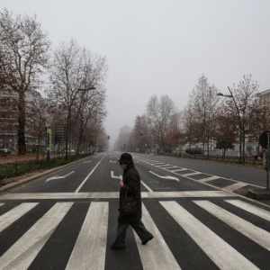 Mulher atravessa a rua em Milão, na Itália, onde os carros estão proibidos de circular - Marco Bertorello/ AFP