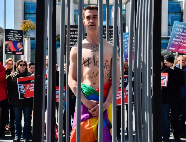 30.abr.2017 - Ativista enrolado com a bandeira símbolo do movimento LGBT protesta em frente a Chancelaria de Berlim - JOHN MACDOUGALL/AFP