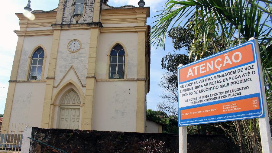 Alerta para o caso de emergência aos moradores do distrito de Barra Feliz, em Santa Bárbara (MG), ao lado da igreja de Nossa Senhora da Conceição - Luciana Quierati/UOL