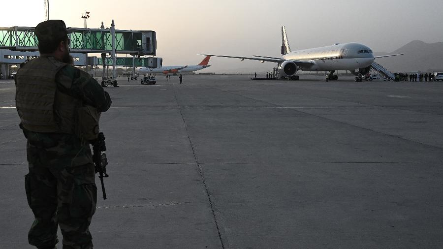 10.set.2021 - Um membro da unidade militar Taliban Badri 313 fica de guarda enquanto os passageiros embarcam em uma aeronave da Qatar Airways com destino ao Catar  - Aamir Qureshi/AFP