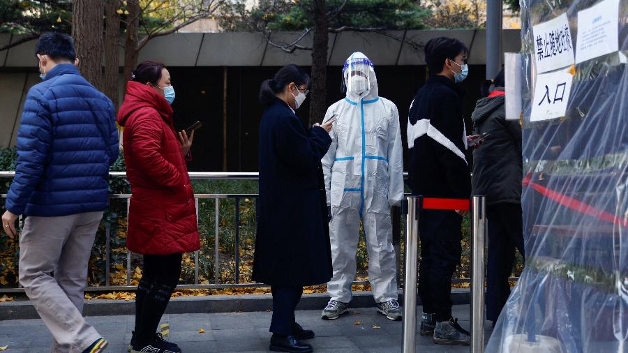 15.nov.22 - Pessoas fazem fila para fazer um teste de ácido nucleico para a doença de coronavírus (COVID-19) em uma cabine de teste perto de um prédio de escritórios no Central Business District (CBD) no distrito de Chaoyang, Pequim, China - TINGSHU WANG/REUTERS