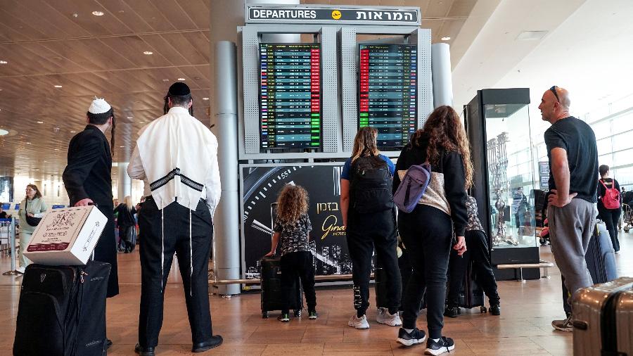 27.mar.23 - Viajantes olham para um monitor que exibe voos atrasados depois que as decolagens foram suspensas como parte de protestos nacionais contra o plano de revisão judicial do governo, de acordo com um porta-voz do aeroporto, no Aeroporto Internacional Ben Gurion em Lod, Israel