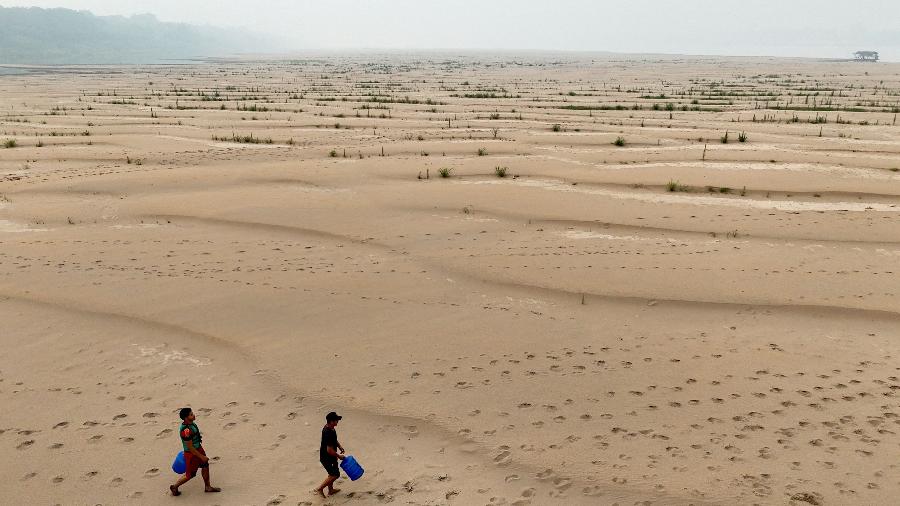 Pessoas carregam água potável ao longo de um banco de areia do Rio Madeira, em Humaitá (AM)