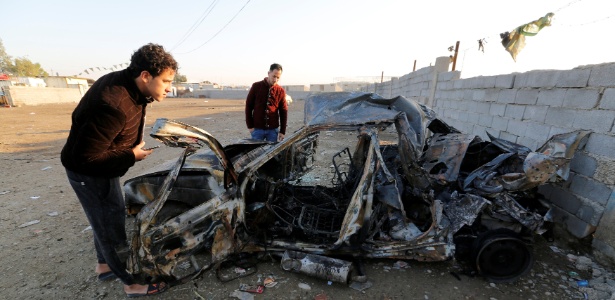 Homens olham destroços de carro-bomba em Sadr City, bairro xiita de Bagdá, no Iraque - Wissm al-Okili/Reuters