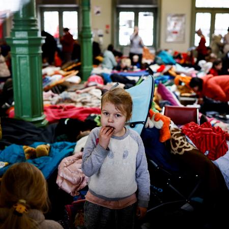 Uma criança come um biscoito enquanto está em uma acomodação temporária para refugiados  - Yara Nardi/Reuters