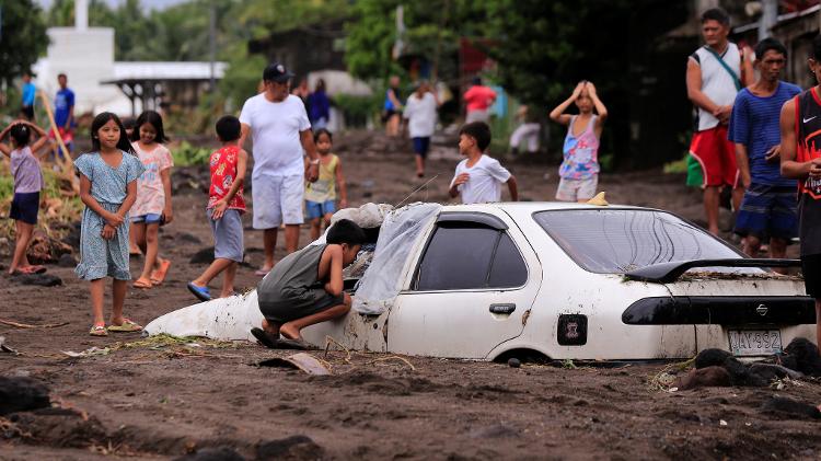 Carro atolado em cinzas vulcânicas carregadas por enchente provocada pela tempestade tropical Trami, ao sul de Manila, nas Filipinas