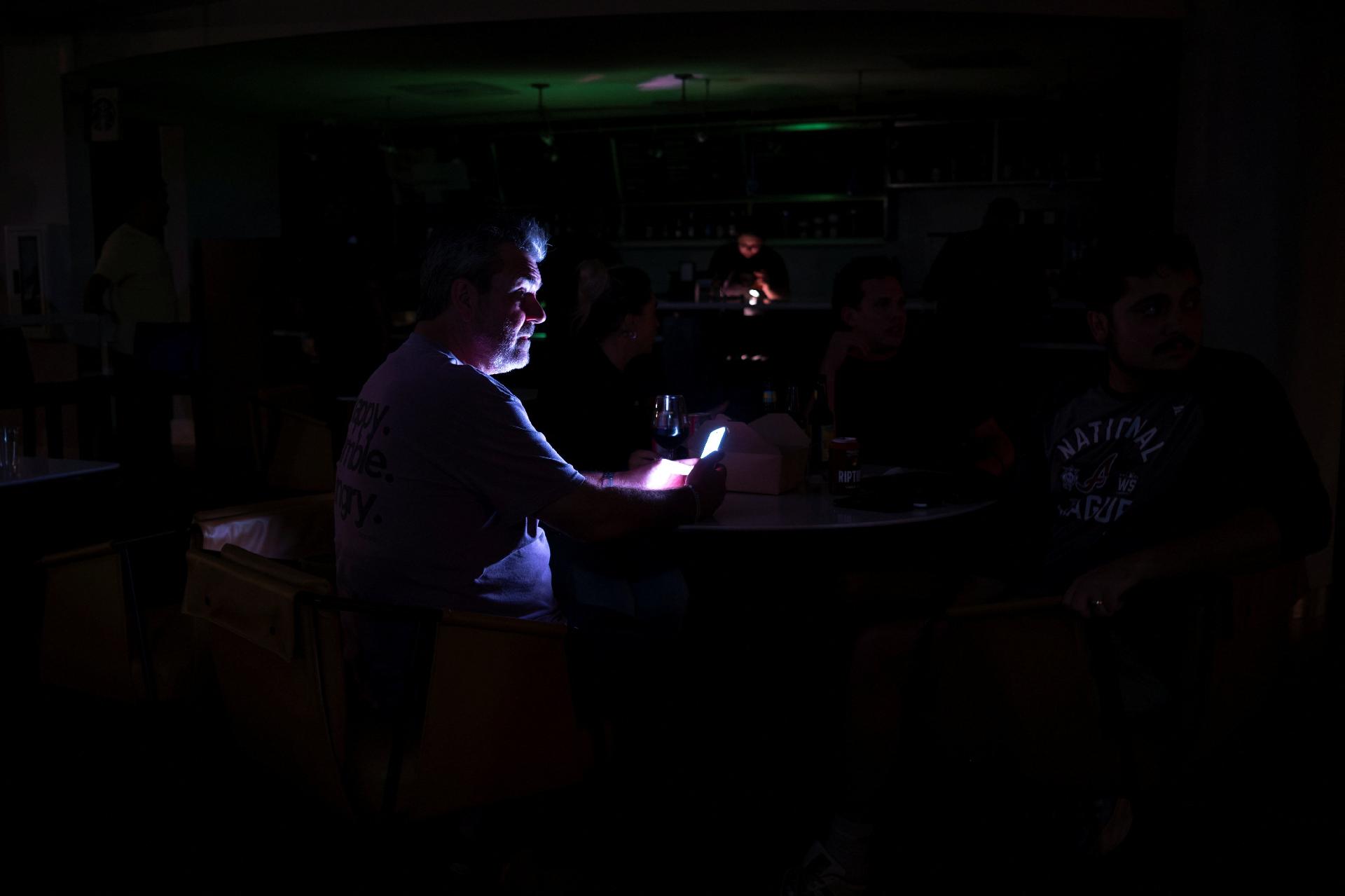 9.out.2026 - Pessoas se reúnem no saguão de um hotel durante falta de energia antes da chegada do furacão Isaias, em Pensacola, na Flórida, nos EUA - undefined