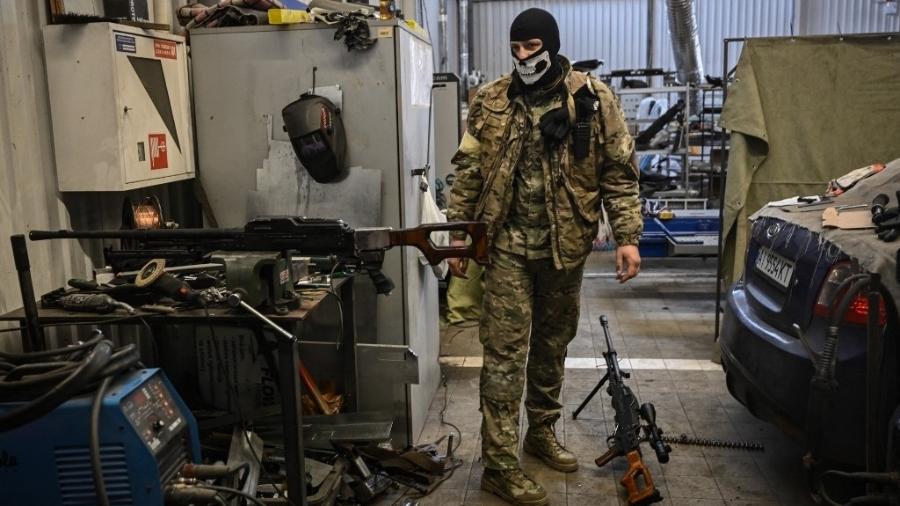 06.mar.2022 - Um voluntário fica dentro de uma oficina mecânica enquanto recondiciona metralhadoras que foram retiradas do exército da Rússia, em Kiev, na capital da Ucrânia. - ARIS MESSINIS/AFP