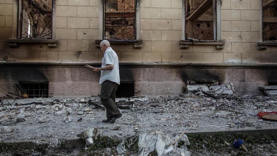 Homem caminha ao lado de prédio danificado por ataque militar na cidade de Lysychansk, na Ucrânia - Oleksandr Ratushniak/Reuters