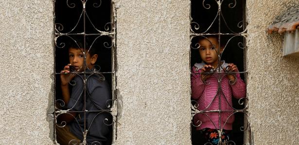 Crianças palestinas observam local bombardeado em Khan Younis, no sul da Faixa de Gaza