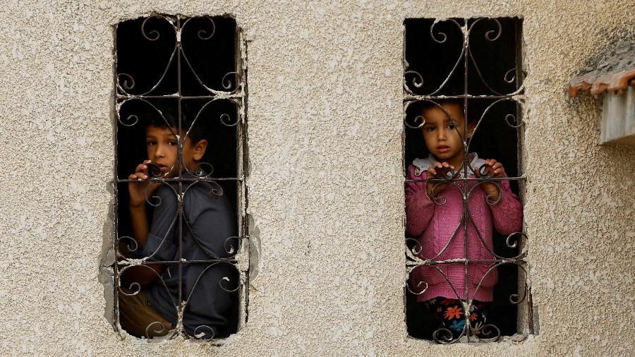 Crianças palestinas observam local bombardeado por Israel em Khan Younis, no sul da Faixa de Gaza