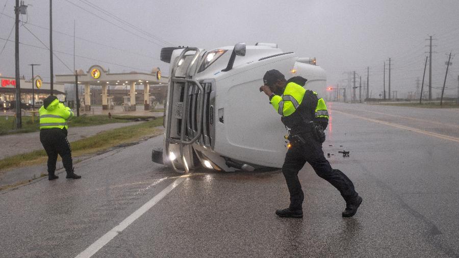 08.jul.24 - Policiais lutam contra os ventos fortes do furacão Beryl enquanto revistam um caminhão semirreboque tombado em busca de ocupantes em Freeport, Texas, EUA