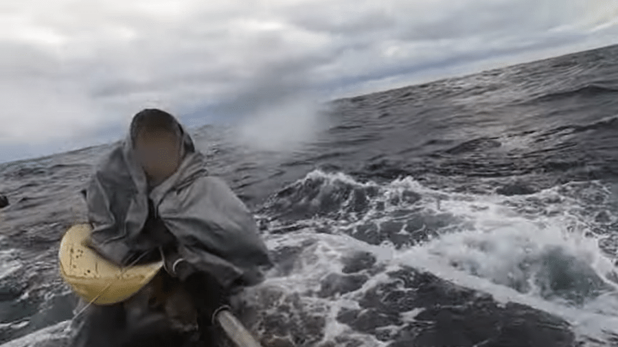 Coberto por um plástico e sentado em um barco tombado, homem de 69 anos ficou 22 horas à deriva no mar. - Guarda Costeira de Kagoshima/AFP