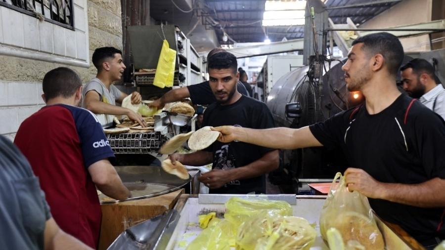 Funcionários de uma padaria em Deir el-Balah, no centro da Faixa de Gaza, enchem sacos com pão fresco, depois que Israel permitiu que ajuda humanitária limitada entrasse no território palestino em 22 de maio de 2025. Funcionários de uma padaria em Deir el-Balah, no centro da Faixa de Gaza, enchem sacos com pão fresco, depois que Israel permitiu que ajuda humanitária limitada entrasse no território palestino em 22 de maio de 2025.