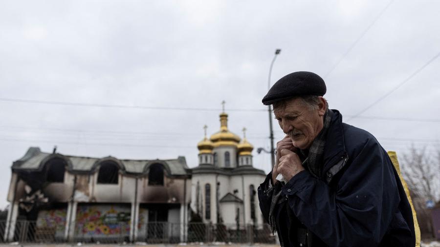 7.mar.2022 - Idoso faz uma pausa enquanto deixa a cidade de Irpin, na Ucrânia, após fortes bombardeios russos - Carlos Barria/Reuters