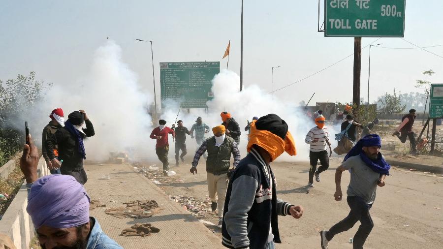 Agricultores se dispersam depois que a polícia disparou gás lacrimogêneo para impedir que eles marchassem em direção a Nova Delhi durante um protesto para exigir preços mínimos para as colheitas, perto da fronteira do estado de Haryana-Punjab, em Shambhu, no distrito de Patiala