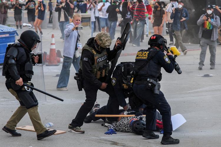 Polícia detém manifestante que bloqueava a entrada da garagem do Edifício Federal de Los Angeles após várias detenções pelo Serviço de Imigração e Alfândega Polícia detém manifestante que bloqueava a entrada da garagem do Edifício Federal de Los Angeles após várias detenções pelo Serviço de Imigração e Alfândega