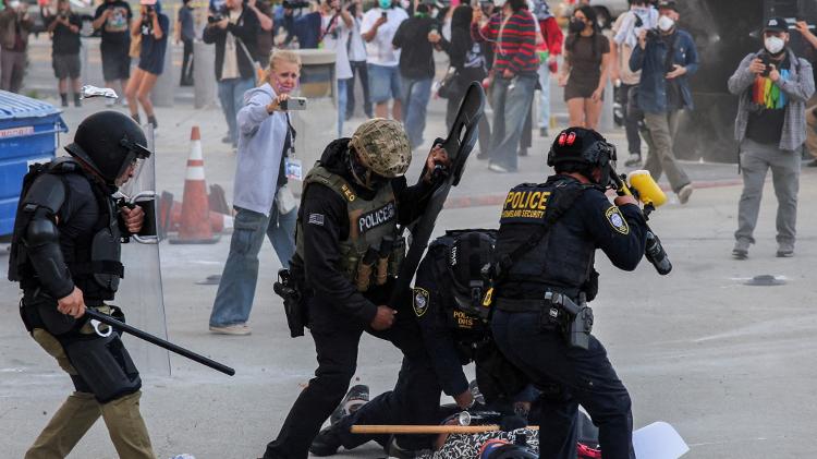 Polícia detém manifestante que bloqueava a entrada da garagem do Edifício Federal de Los Angeles após várias detenções pelo Serviço de Imigração e Alfândega Polícia detém manifestante que bloqueava a entrada da garagem do Edifício Federal de Los Angeles após várias detenções pelo Serviço de Imigração e Alfândega