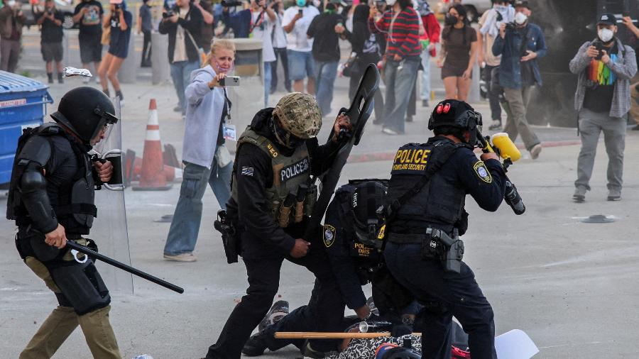 Polícia detém manifestante que bloqueava a entrada da garagem do Edifício Federal de Los Angeles após várias detenções pelo Serviço de Imigração e Alfândega Polícia detém manifestante que bloqueava a entrada da garagem do Edifício Federal de Los Angeles após várias detenções pelo Serviço de Imigração e Alfândega