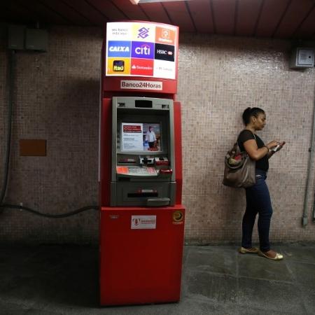 Mulher utiliza o celular ao lado de caixa eletrônico no Rio de Janeiro - PILAR OLIVARES