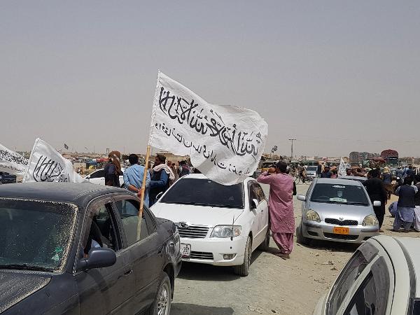 17.ago.2021 - Pessoas se reúnem em torno de uma bandeira do Taleban enquanto esperam por parentes libertados da prisão no Afeganistão após uma 'anistia' do Taleban - AFP