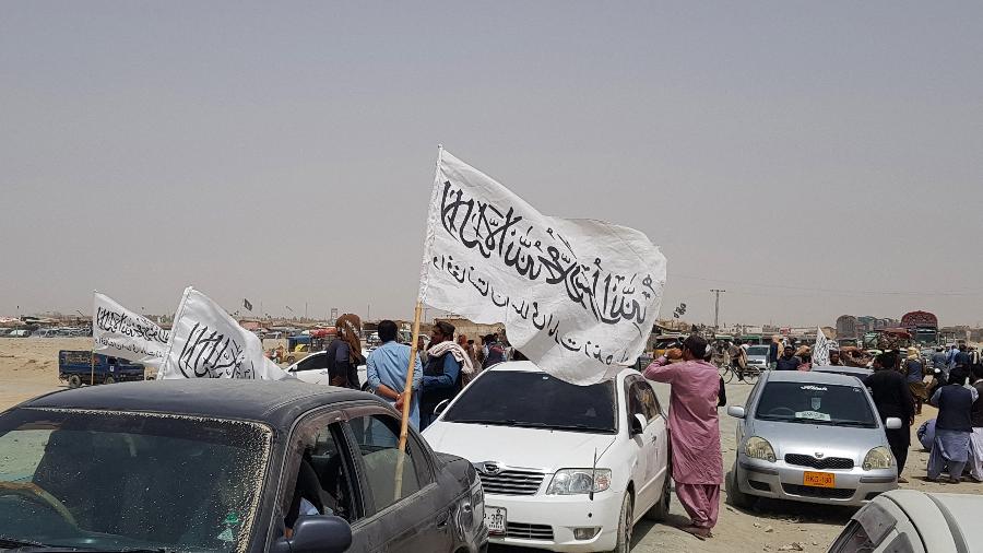 17.ago.2021 - Pessoas se reúnem em torno de uma bandeira do Taleban enquanto esperam por parentes libertados da prisão no Afeganistão após uma "anistia" do Taleban - AFP