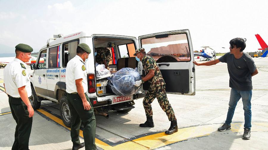 Militares transferem cadáveres congelados recuperados do Everest para uma ambulância para cremação no Aeroporto Internacional de Tribhuvan, em Katmandu