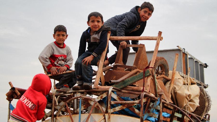 15.fev.2020 - Crianças se equilibram em cima de um caminhão-pipa cheio de objetos, no vilarejo rural Saharah, entre as províncias de Aleppo e Idlib, enquanto pessoas fogem dessas regiões, afetadas por ações militares do governo da Síria - Ibrahim Yasouf/AFP
