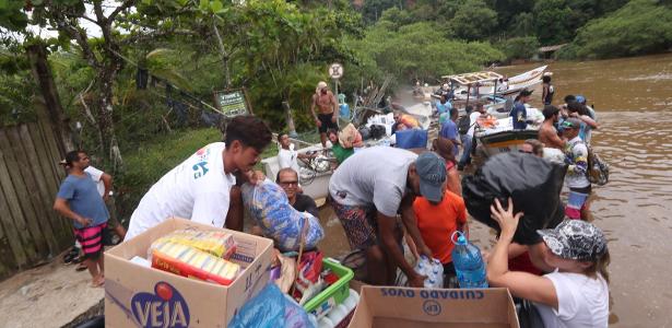 Turistas e moradores usam barcos pelo rio Sahy para deixar a região 