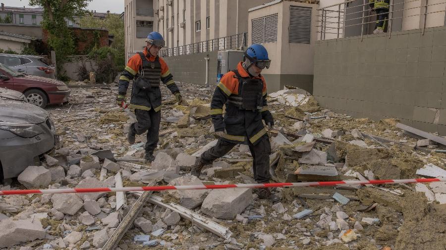 Equipes de emergência caminham entre os escombros em frente a um prédio residencial danificado por um ataque com mísseis em Kharkiv, em 14 de maio de 2024